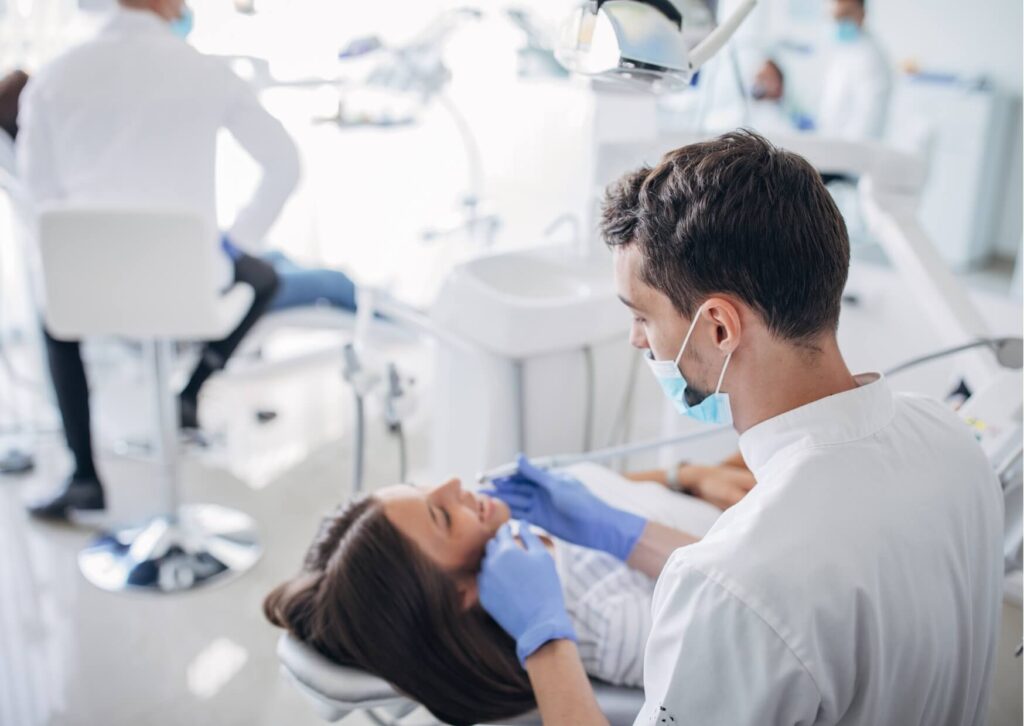 Dentist examining a patient during a restorative consultation to discuss treatment options for fixing grinded teeth and repairing enamel wear.