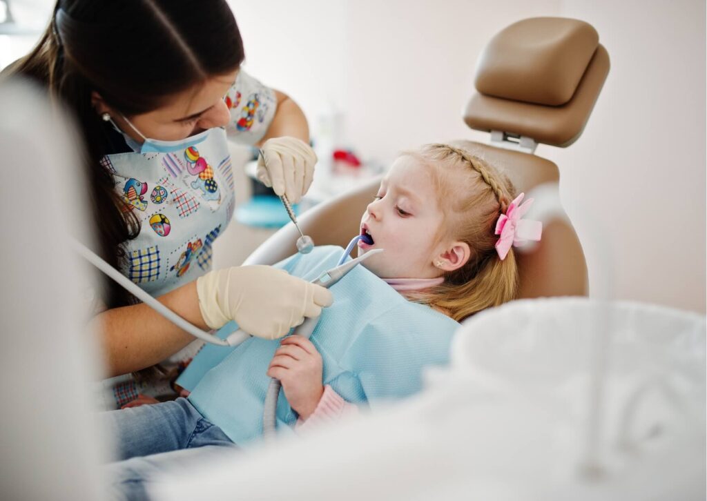 Young child receiving a dental exam from a pediatric dental professional, illustrating when to take your child to the dentist for early preventive care and routine checkups.