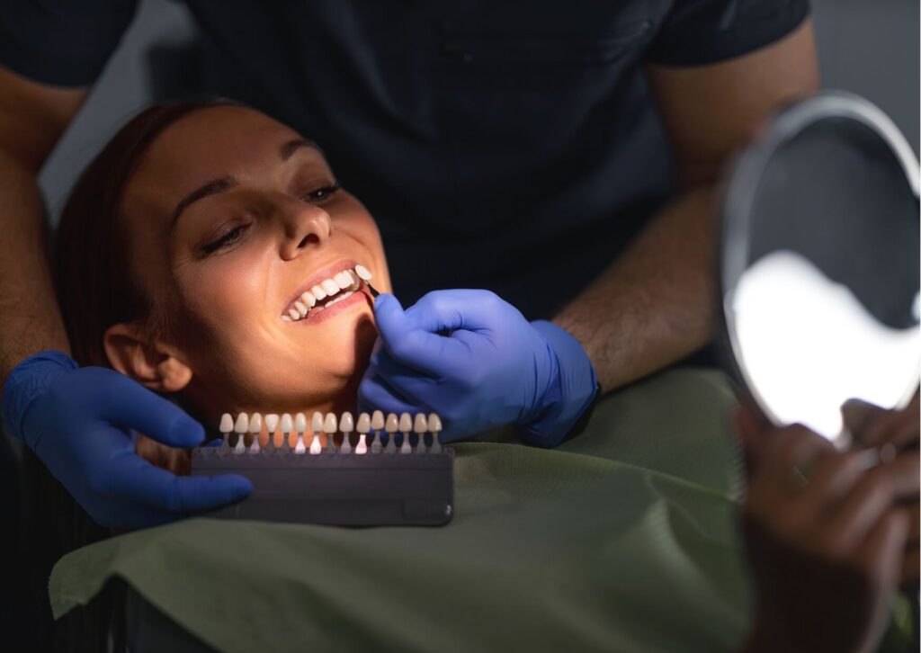 Patient comparing tooth shades during a cosmetic dental consultation about teeth whitening strips effectiveness and professional whitening results.